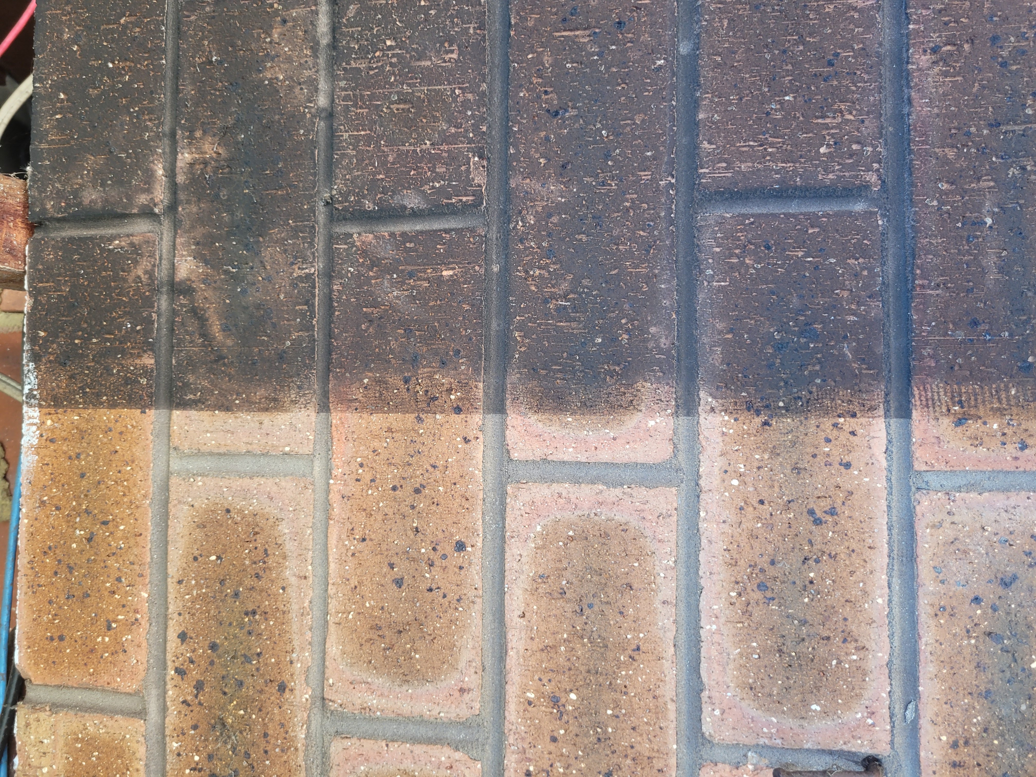 Brick wall with half cleaned and half soot-covered surface showing fire damage restoration progress