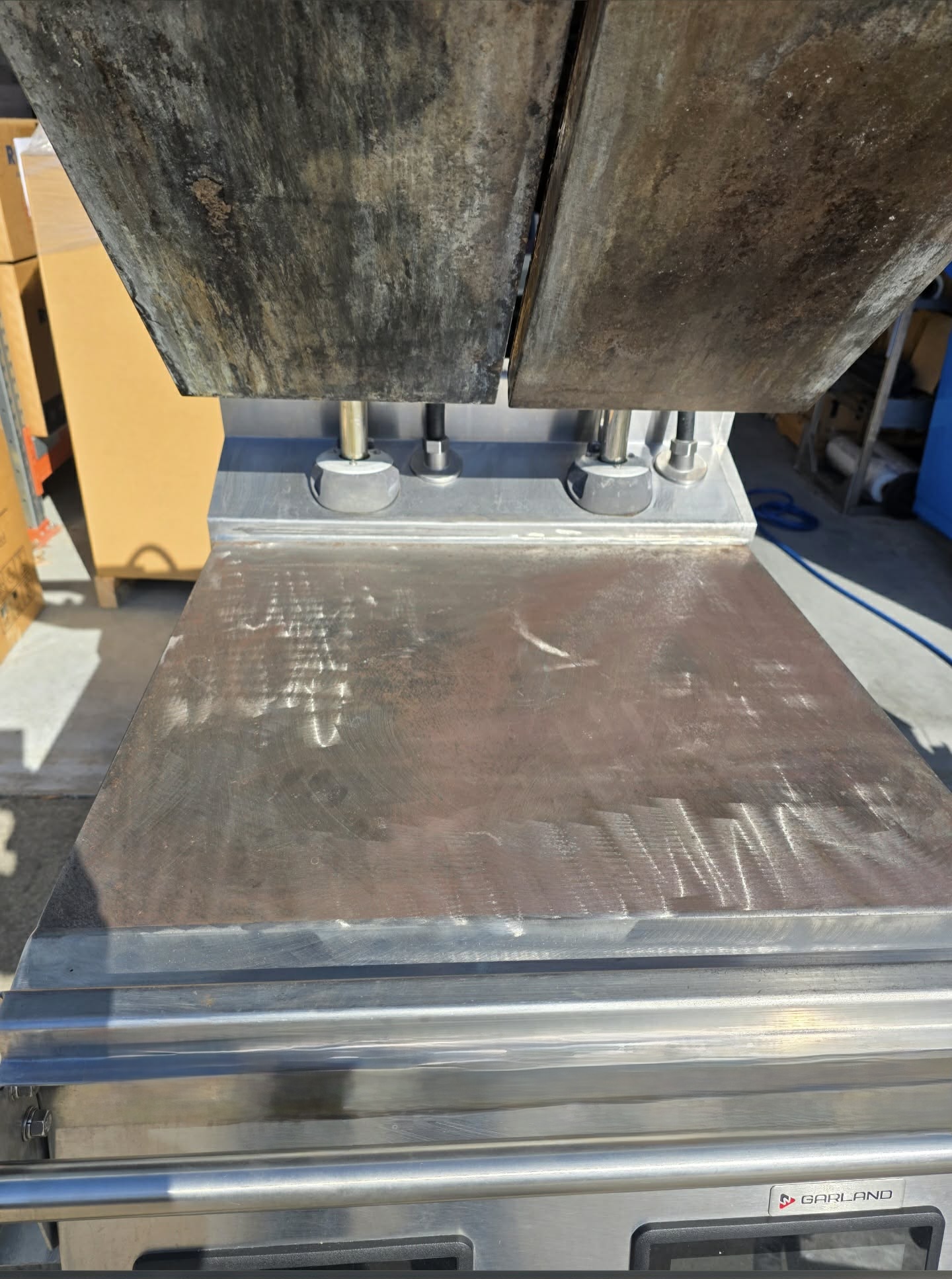 Commercial kitchen flat top griddle covered in baked-on grease before laser cleaning