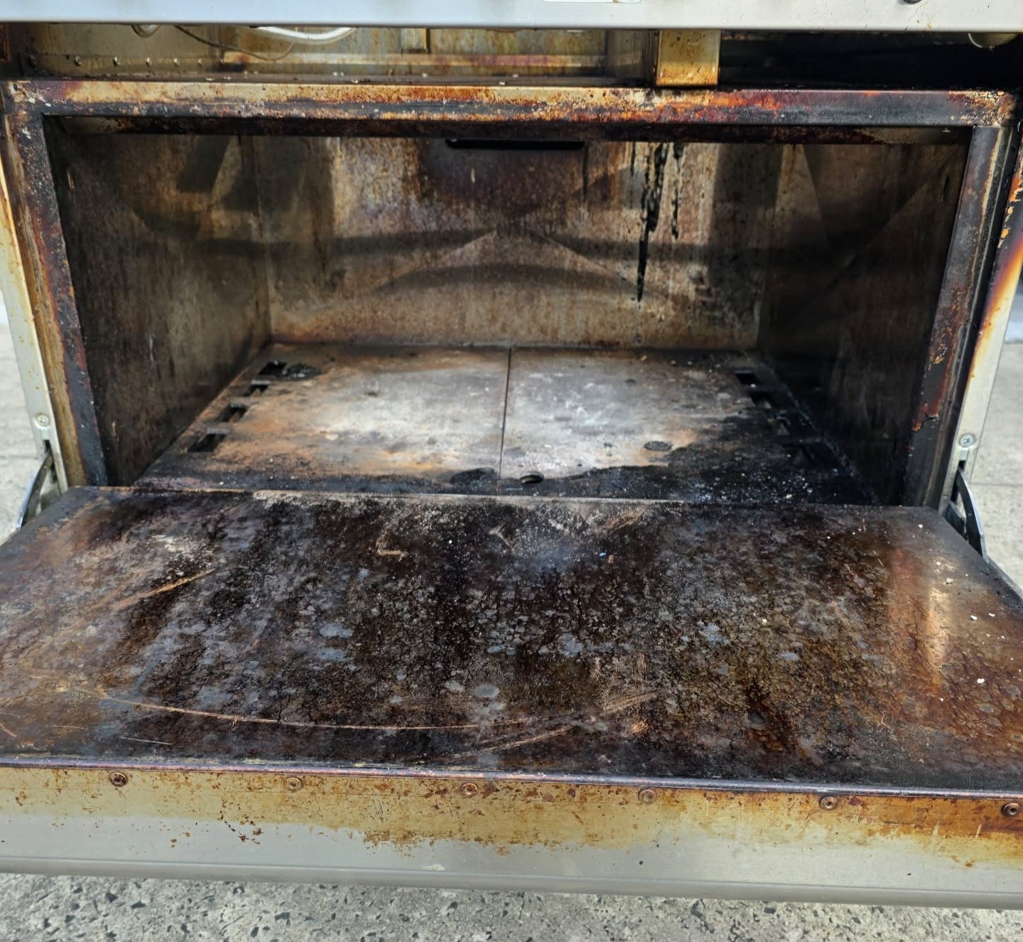 Commercial oven interior with heavy carbonized grease buildup before laser cleaning